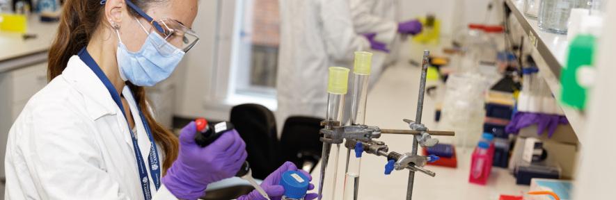 Female researcher in PPE and lab coat working in lab